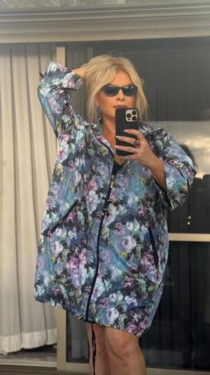 Женщина в голубой ветровке с цветочным принтом на солнце